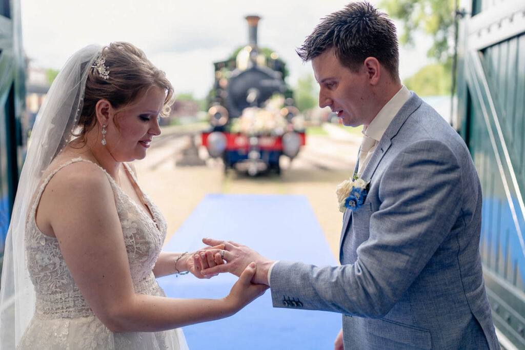 De ringen omdoen met de stoomlocomotief op de achtergrond tijdens de ceremonie bij de MBS in Boekelo.