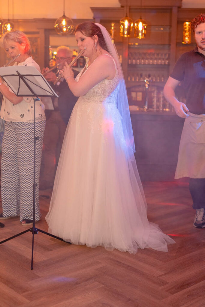 fluit spelende bruid tijdens avondfeest. foto gemaakt tijdens trouwreportage bij het haagen in haaksbergen.