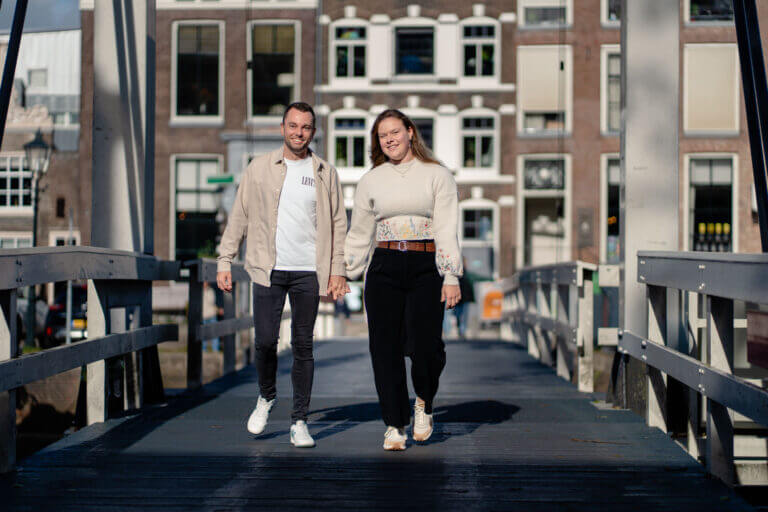 Koppel hand in hand lopend over brug tijdens koppelshoot in Zwolle